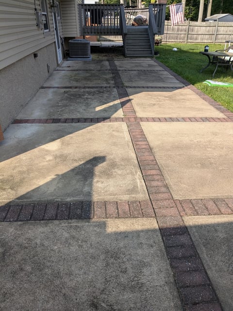 Driveway with mixed concrete and brick pavers leading to black gate and garage, residential home exterior